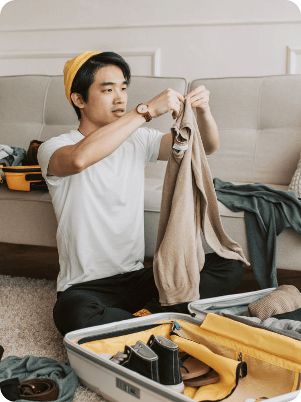 Expat wearing a yellow hat preparing his luggage before relocating to Berlin