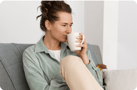 Woman drinking tea on a sofa.