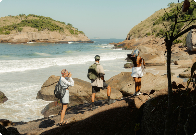Three people hiking on a sunny day next to the ocean during their vacation. 