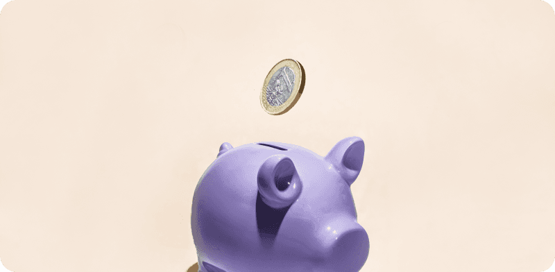 A single euro coin in mid-air above a purple piggy bank, set against a light beige background.