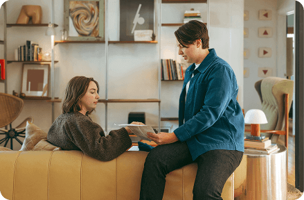 Two people in their cosy apartment, sitting on a couch and talking.