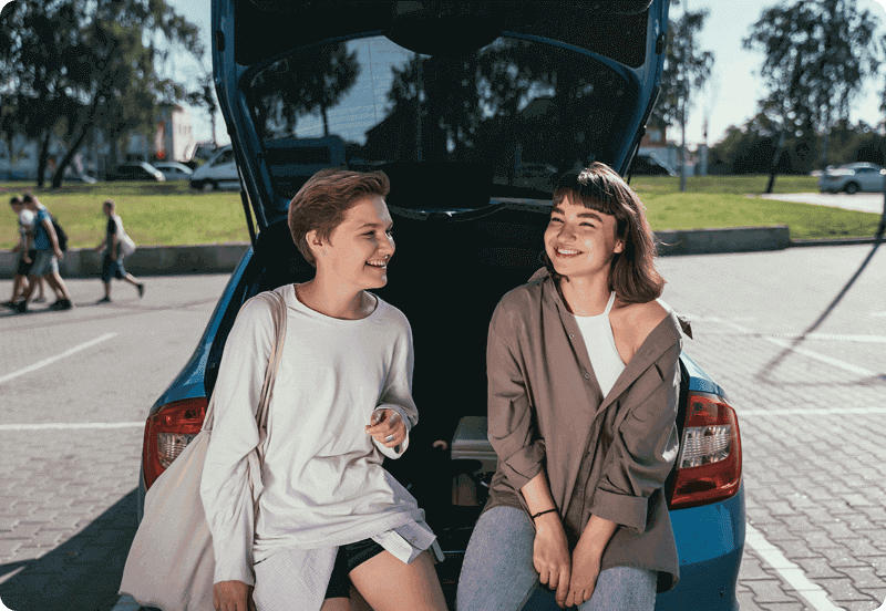 Two friends hanging out by their car