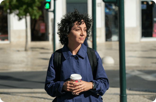 a woman in the middle of the street with her coffee