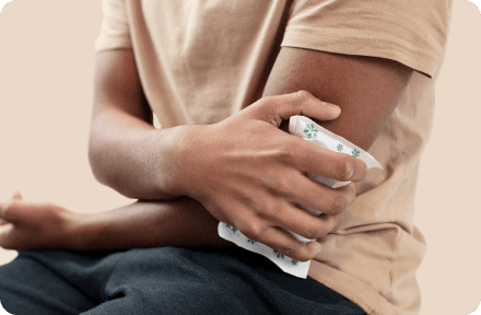 Person in a beige shirt holding an ice pack against their injured elbow