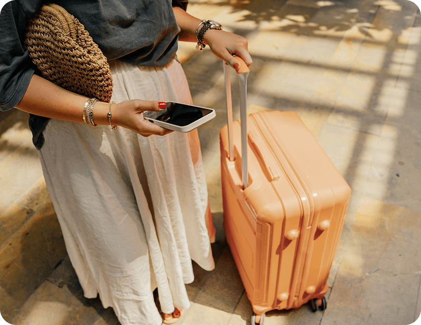 Woman traveling with her suitcase, looking at her phone.