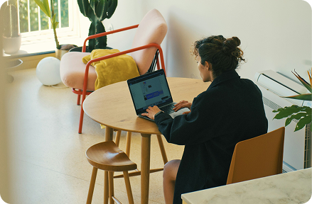 Person sitting at a table and working on a laptop.