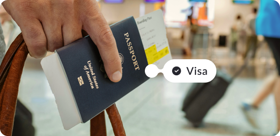 Person holding a passport in their hand at the airport. The tag reads "Visa" with a checkmark.