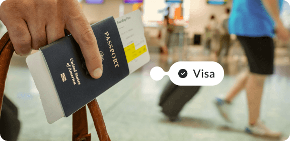 Person holding a passport in their hand at the airport. The tag reads "Visa" with a checkmark.