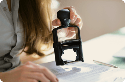 Person at a public office approving visa documents with a stamp.