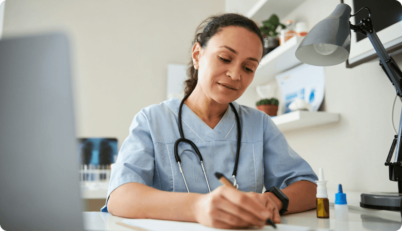 A doctor in her office writing a prescription.