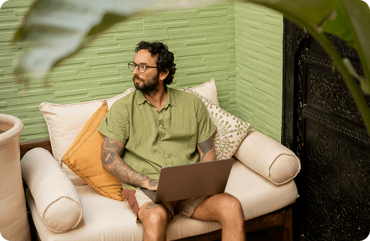 Man sitting on a couch, working on his laptop.