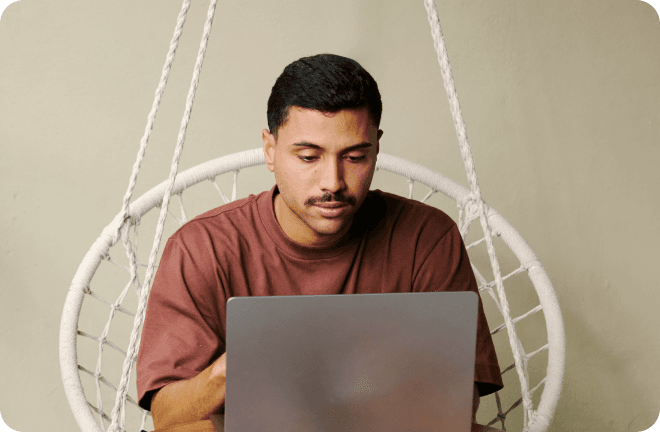 A young man sitting, working on a laptop.