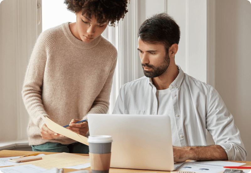 Two colleagues checking the available insurance plans that their company provided to them on a laptop.