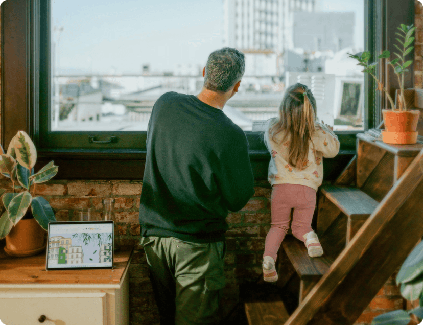 Father and a daughter looking through a window showing sky and city buildings.