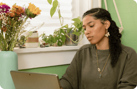 Girl sitting in her apartment and looking at a laptop screen.
