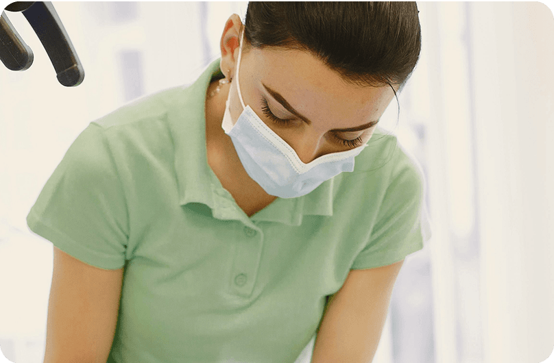 Dentist wearing a mask, working. Overlayed graphic reads "stiftung warentest finanztest Sehr gut (1,1) Mehr Zahn 90".