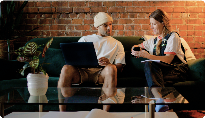 Person sitting on a couch showing her phone to a man sitting next to her.